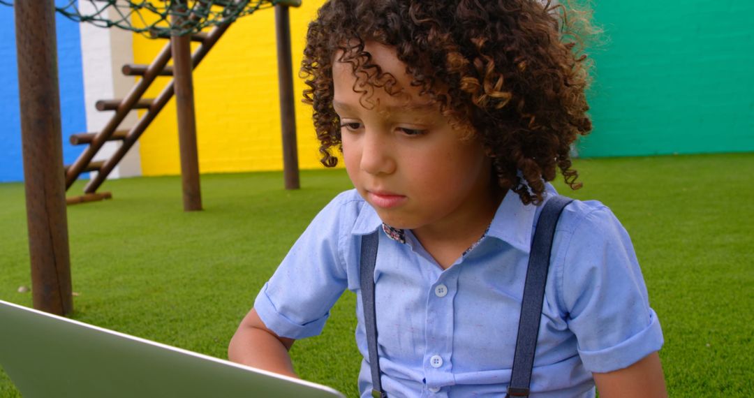 Curly Haired Boy Using Laptop in Outdoor Playground