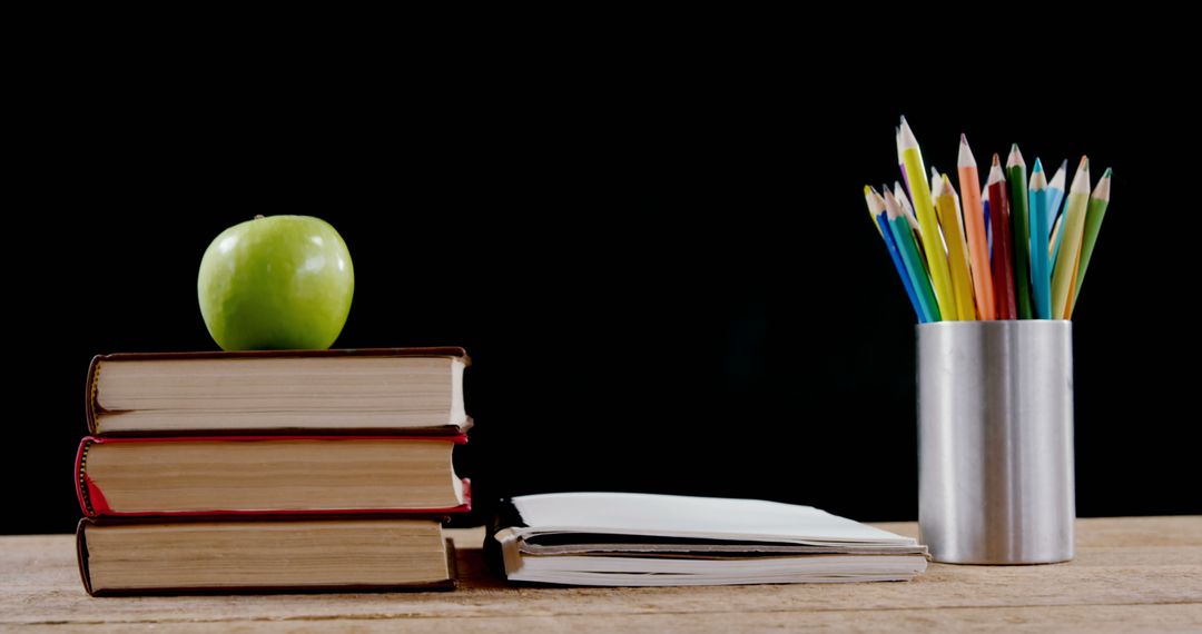 Stacked Books with Green Apple and Colorful Pencils Symbolize Education