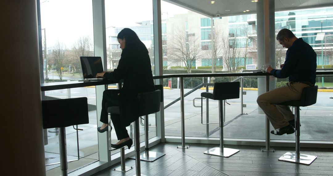 People Working on Portable Devices By Window in Modern Office - Free Images, Stock Photos and Pictures on Pikwizard.com