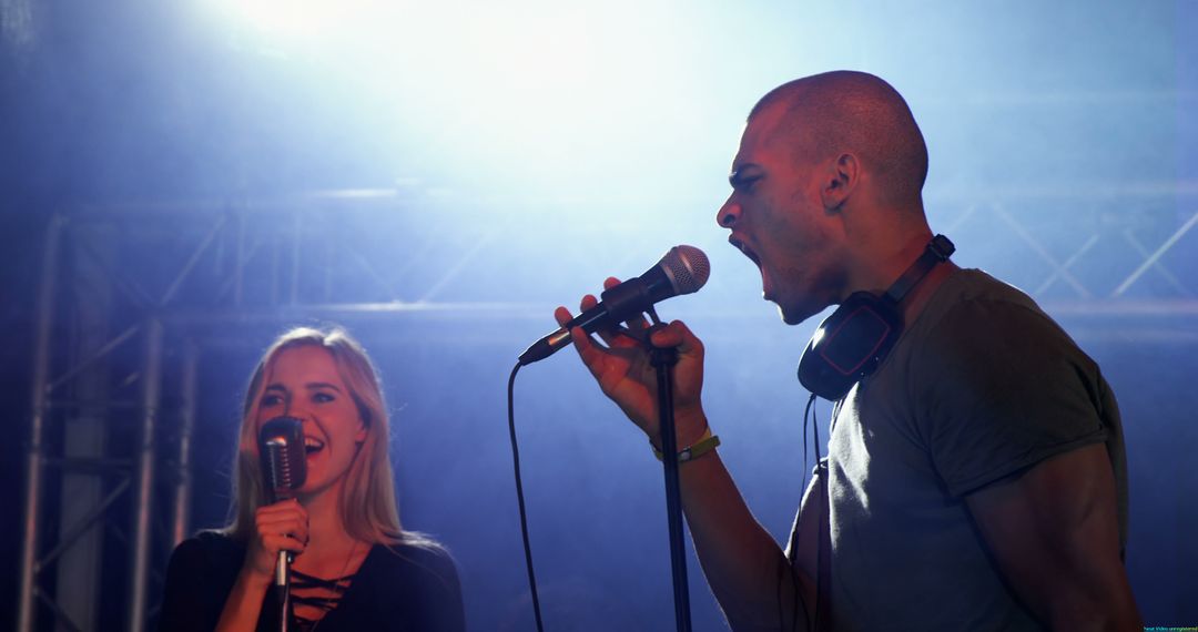 Energetic Duo Singing on Stage with Microphones Under Spotlight - Free Images, Stock Photos and Pictures on Pikwizard.com