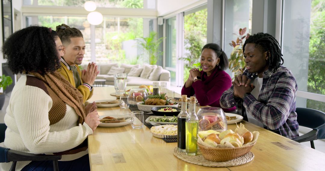 Diverse friends enjoying shared meal at wooden dining table in bright open living room