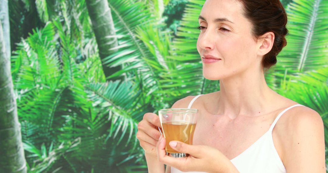 Woman Enjoying Beverage Amidst Tropical Greenery - Free Images, Stock Photos and Pictures on Pikwizard.com