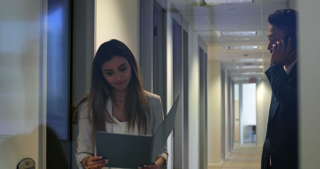 Businessman on Mobile Phone, Coworker Carrying File in Office Hallway