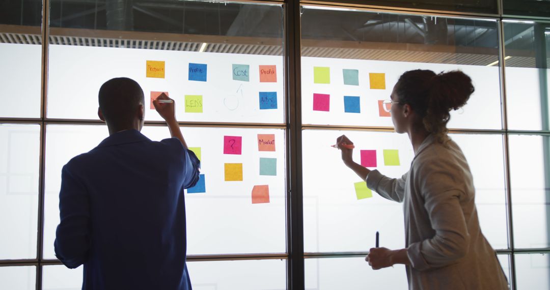 Creative Team Collaborating with Sticky Notes on Office Glass Wall - Free Images, Stock Photos and Pictures on Pikwizard.com