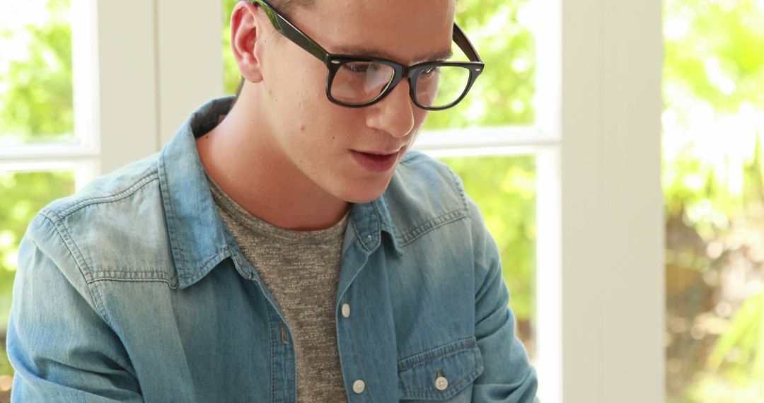 Young Man Learning at Home in Casual Outfit with Large Glasses - Free Images, Stock Photos and Pictures on Pikwizard.com