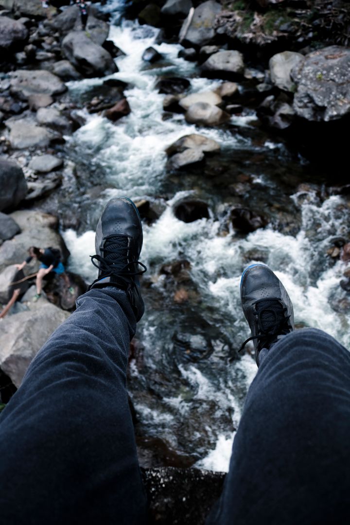 Person Sitting with Feet Dangling Over Fast-Flowing Stream - Free Images, Stock Photos and Pictures on Pikwizard.com