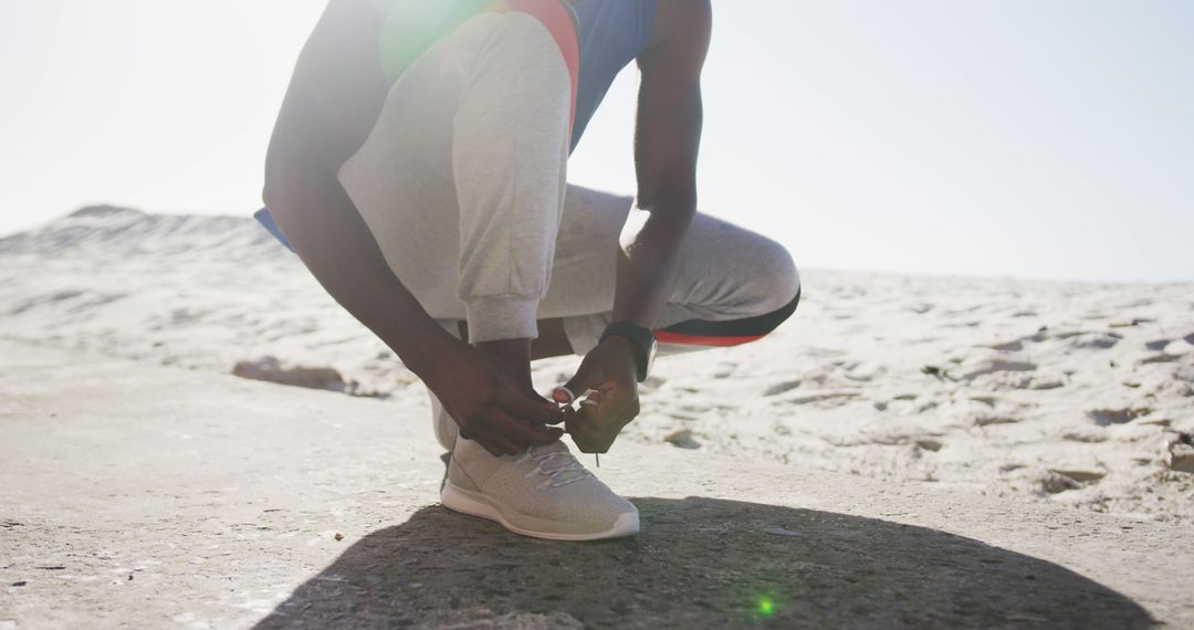 African American Man Tying Shoelaces on Running Shoes on Sunny Beach - Free Images, Stock Photos and Pictures on Pikwizard.com