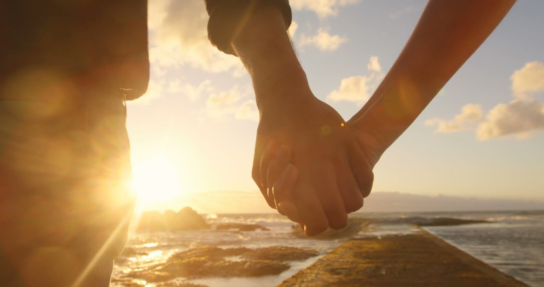 Romantic Couple Holding Hands at Sunset by Ocean - Free Images, Stock Photos and Pictures on Pikwizard.com