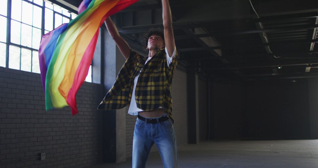 Young Person Waving Rainbow Flag in Industrial Building - Free Images, Stock Photos and Pictures on Pikwizard.com