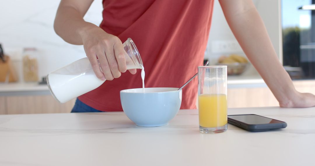 Young Man Preparing Breakfast with Milk and Juice in Modern Kitchen