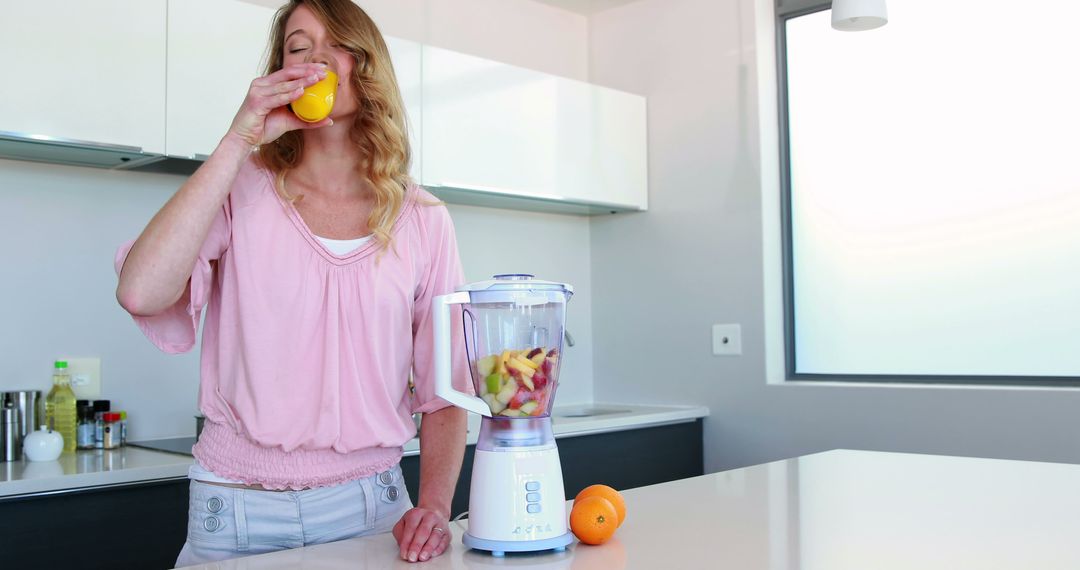 Woman Drinking Fresh Juice in Modern Kitchen with Blending Fruits - Free Images, Stock Photos and Pictures on Pikwizard.com