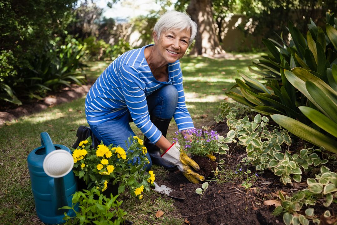 Portrait of smiling senior woman kneeling while planting flowers - Free Images, Stock Photos and Pictures on Pikwizard.com