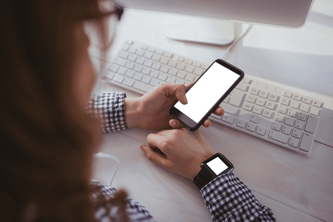 Business Professional Checking Smartphone and Smartwatch on Desk