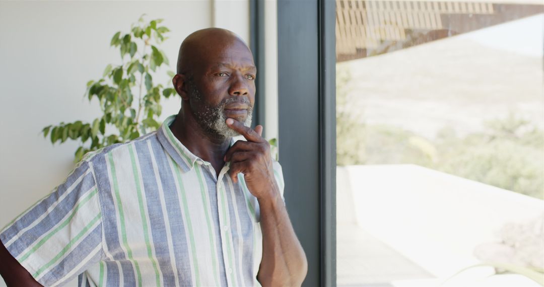 Pensive Mature Man Gazing Out of Window in Thoughtful Reflection