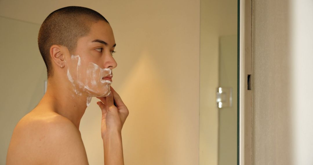 Young Person with Short Hair Applying Facial Cream in Front of Mirror - Free Images, Stock Photos and Pictures on Pikwizard.com