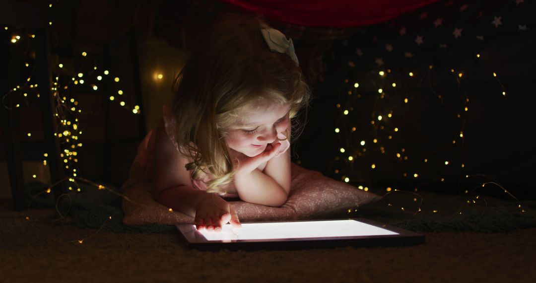 Child Engaged with Tablet in Cozy Setup with Fairy Lights