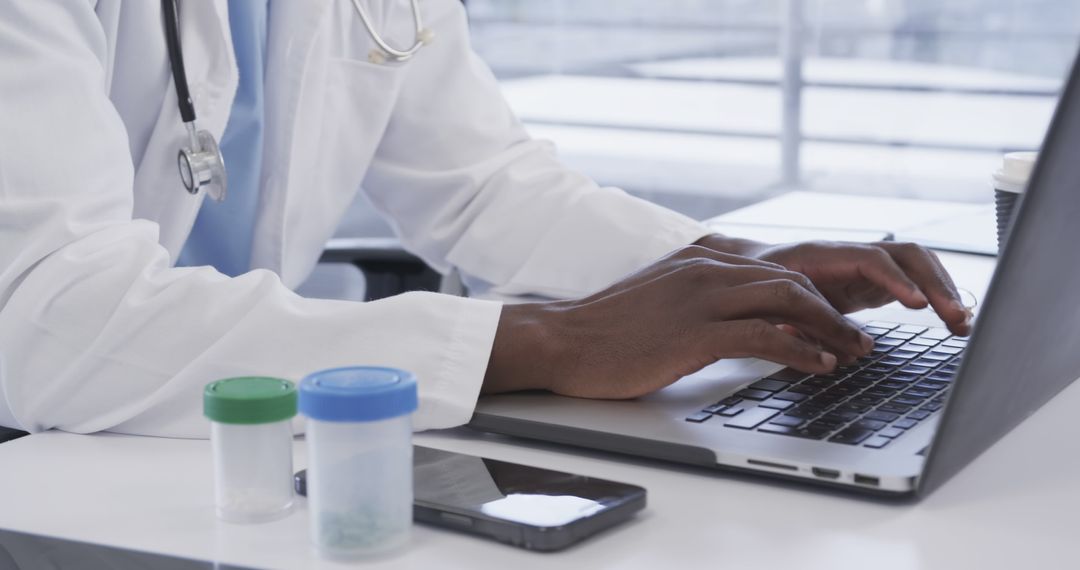 Doctor Typing on Laptop in Office with Medical Tools Nearby - Free Images, Stock Photos and Pictures on Pikwizard.com