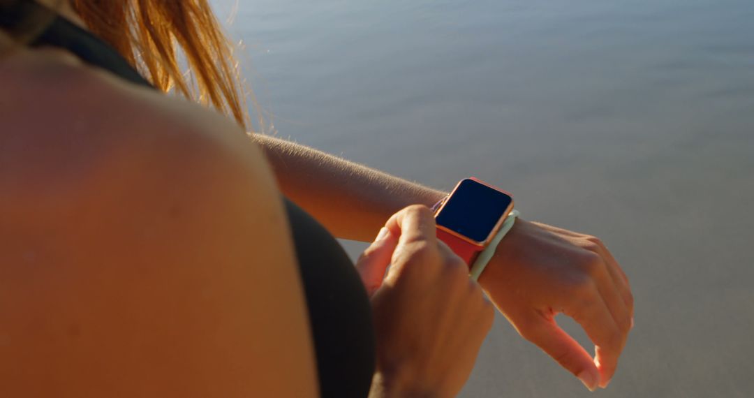 Woman Checking Smartwatch Timer During Beach Run - Free Images, Stock Photos and Pictures on Pikwizard.com