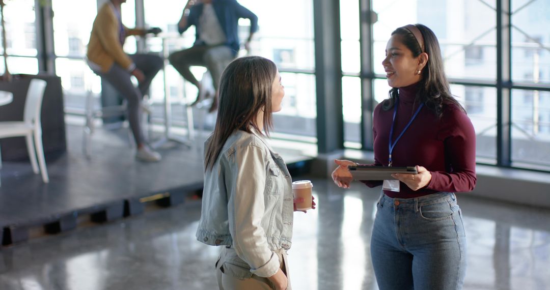 Diverse female coworkers talking and networking in modern open-plan coworking space