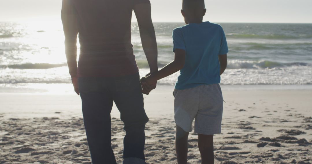 Father and Son Holding Hands Walking on Beach at Sunset - Free Images, Stock Photos and Pictures on Pikwizard.com