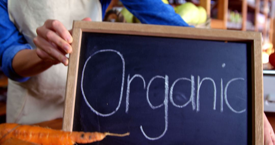 Person Holding Wooden Chalkboard Reading Organic at Farmers Market - Free Images, Stock Photos and Pictures on Pikwizard.com