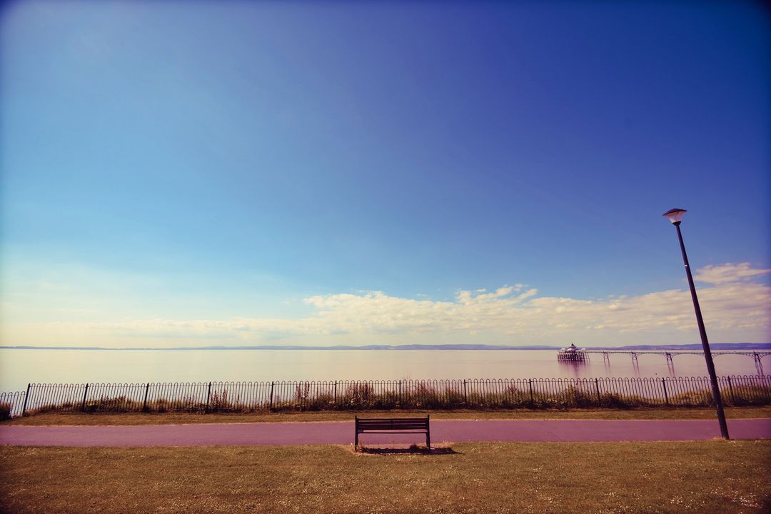 Empty Bench by Serene Waterfront on Clear Day - Free Images, Stock Photos and Pictures on Pikwizard.com