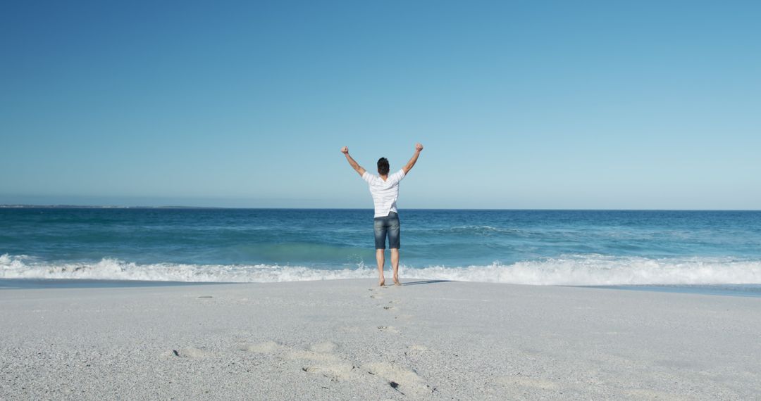 Man Celebrating on Beach with Open Arms Under Clear Sky - Free Images, Stock Photos and Pictures on Pikwizard.com