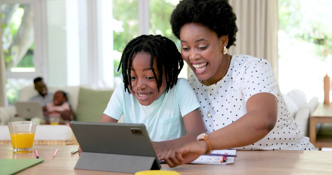 Happy Mother Assisting Son with Homework on Tablet at Home