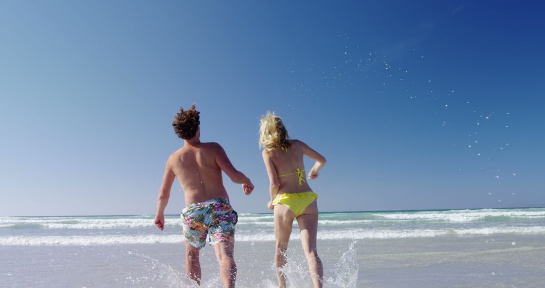 Joyful couple running into ocean on a bright sunny beach - Free Images, Stock Photos and Pictures on Pikwizard.com