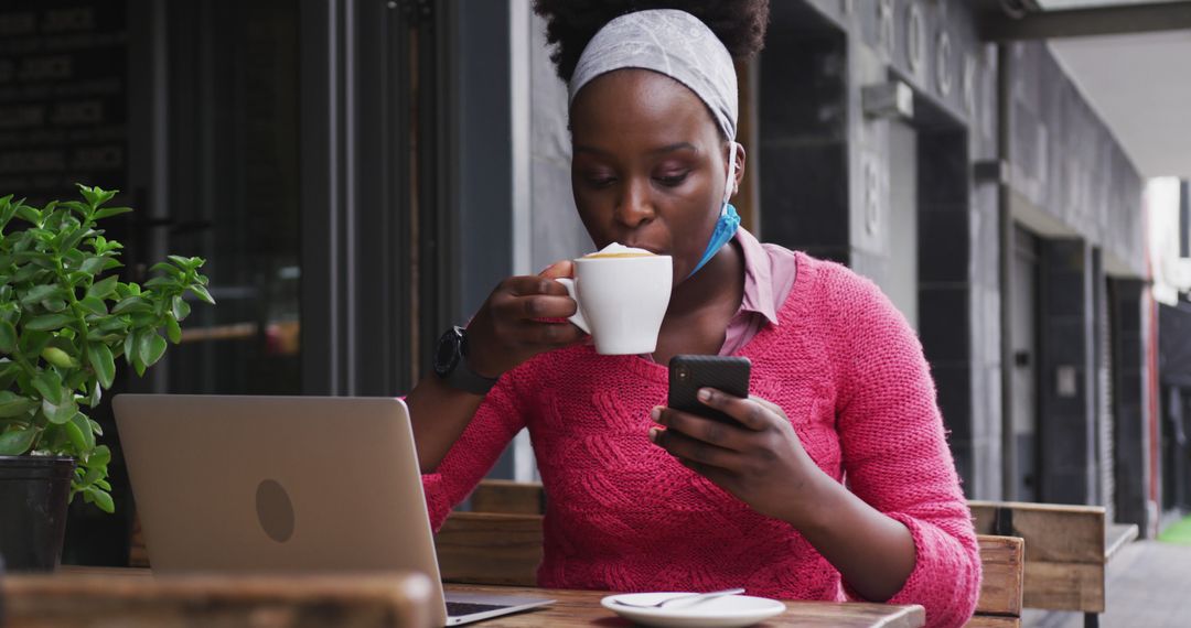 Woman in Pink Sweater Drinking Coffee and Using Smartphone at Outdoor Cafe - Free Images, Stock Photos and Pictures on Pikwizard.com