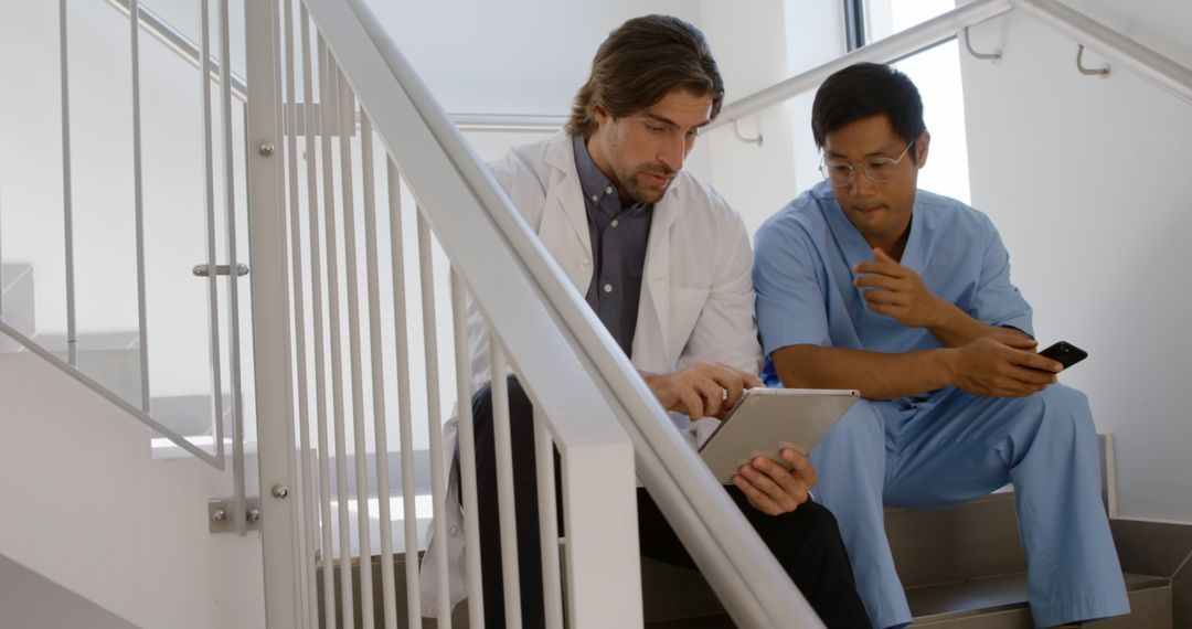 Two Professional Doctors Collaborating on Staircase with Tablet - Free Images, Stock Photos and Pictures on Pikwizard.com