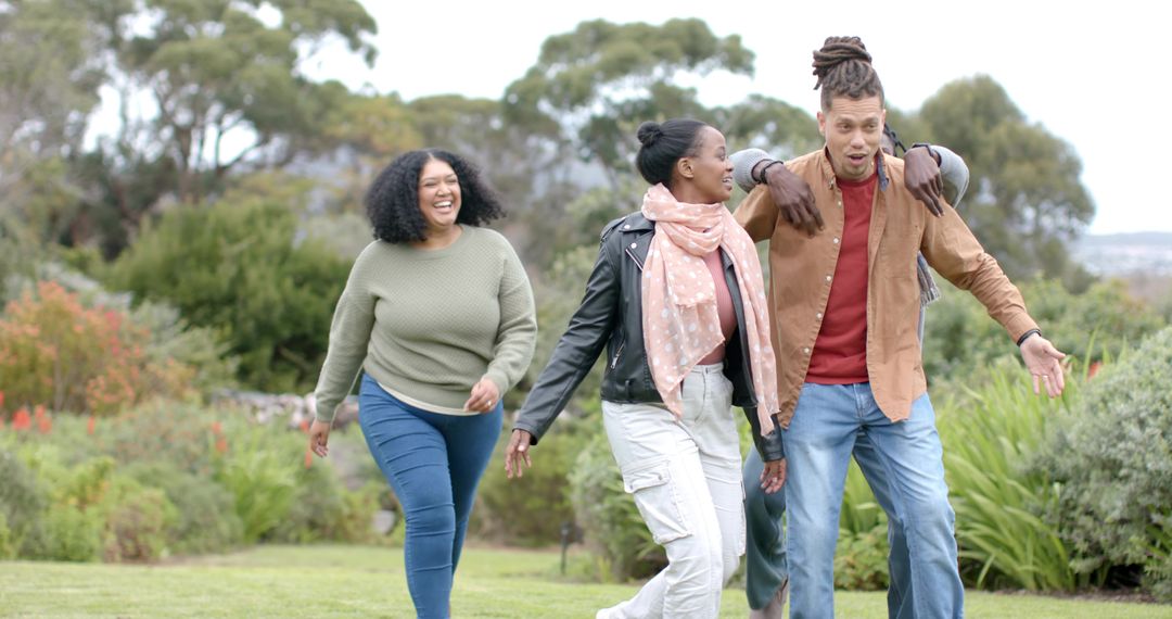 Multiracial friends walking together in park on overcast day enjoying conversation