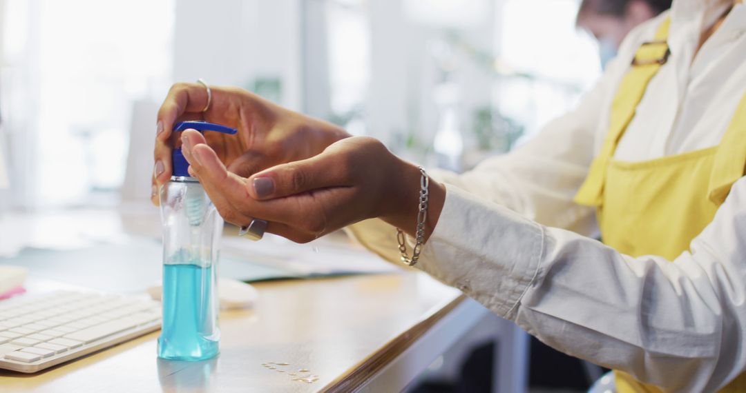 Person Using Hand Sanitizer in Office for Hygiene and Safety - Free Images, Stock Photos and Pictures on Pikwizard.com