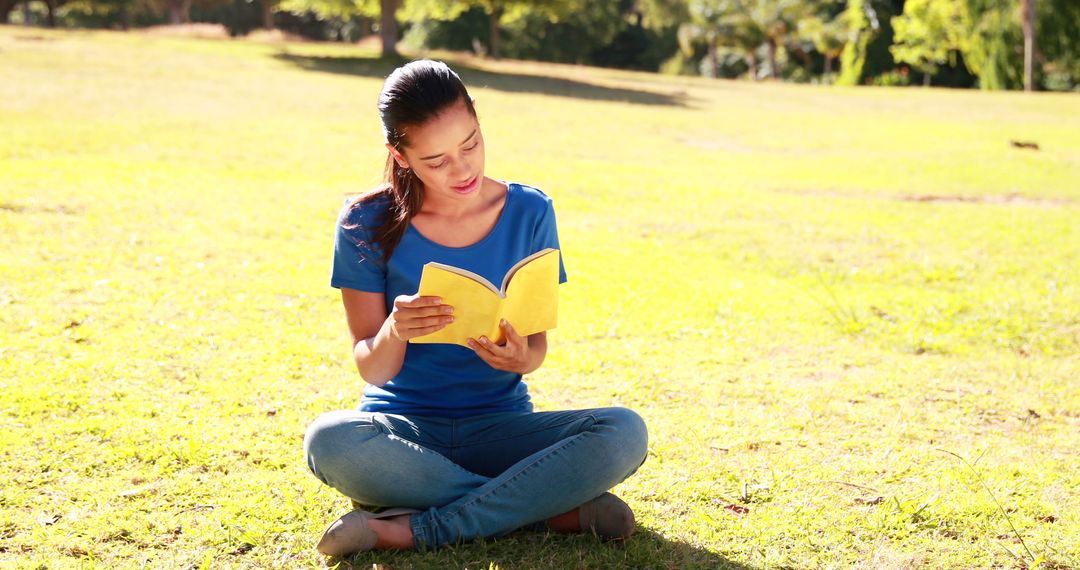 Young Woman Reading Book Outdoors in Sunny Park - Free Images, Stock Photos and Pictures on Pikwizard.com