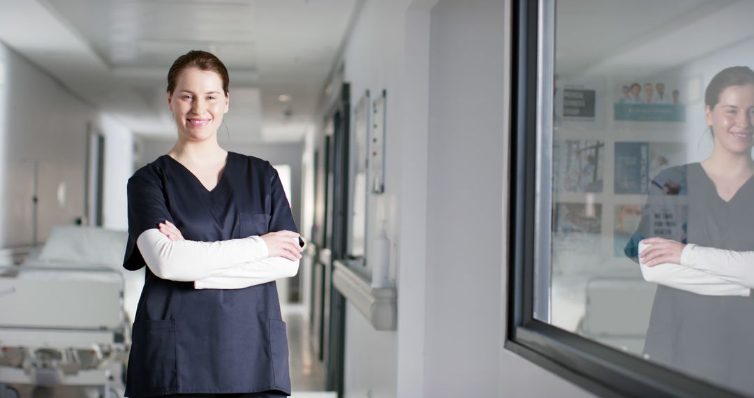 Confident Female Nurse Smiling with Arms Crossed in Hospital Hallway - Free Images, Stock Photos and Pictures on Pikwizard.com