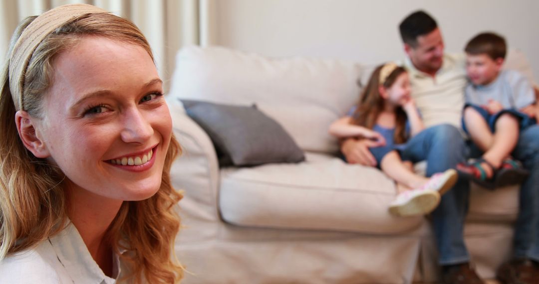 Smiling Woman with Family Relaxing on Couch in Background - Free Images, Stock Photos and Pictures on Pikwizard.com