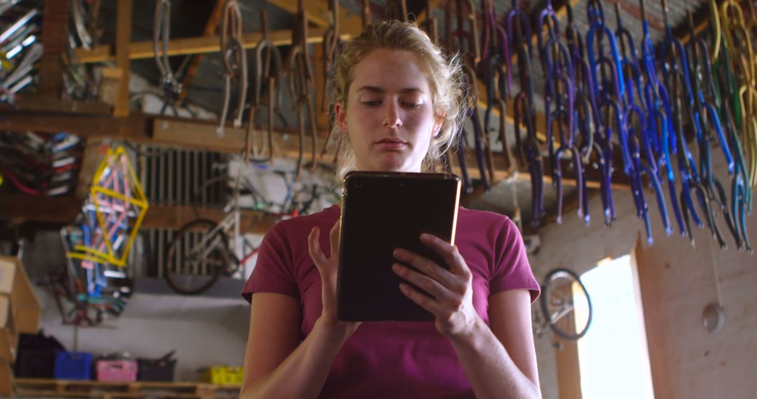 Young woman working with tablet in bicycle repair shop - Free Images, Stock Photos and Pictures on Pikwizard.com