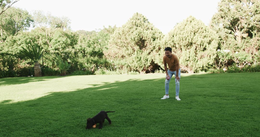 Young Man Playing with Puppy in Sunlit Garden