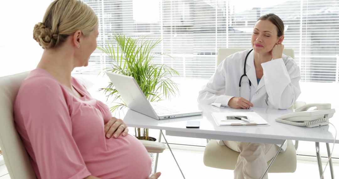 Pregnant Woman Consulting with Doctor in Bright Modern Office - Free Images, Stock Photos and Pictures on Pikwizard.com