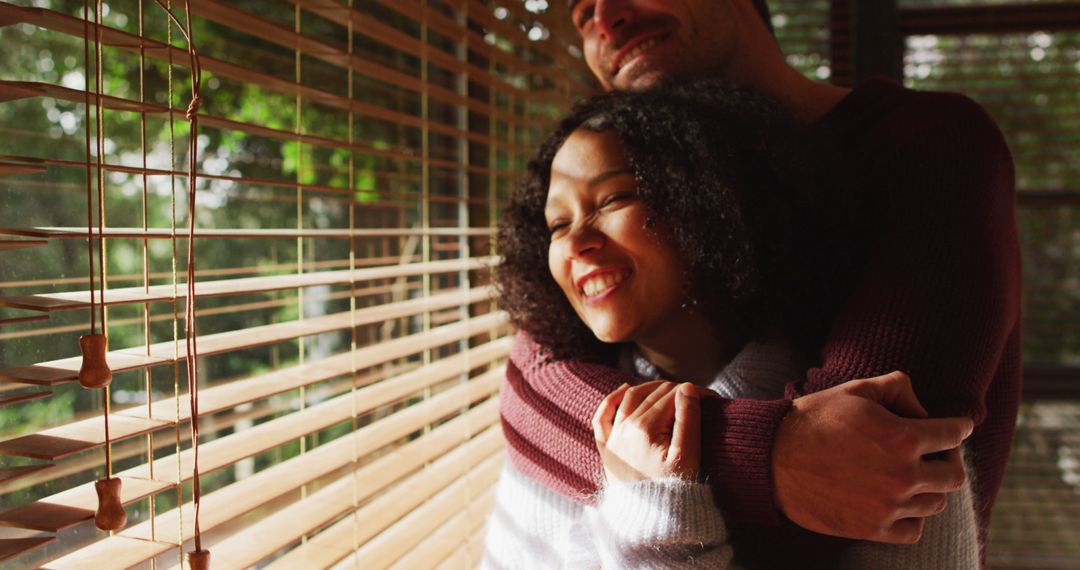 Happy Romantic Couple Embracing Near Window While Smiling - Free Images, Stock Photos and Pictures on Pikwizard.com