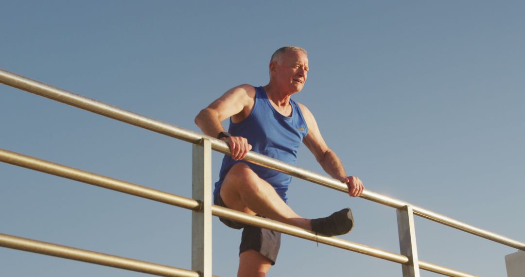 Senior Man Stretching on Outdoor Rail in Morning Sun - Free Images, Stock Photos and Pictures on Pikwizard.com