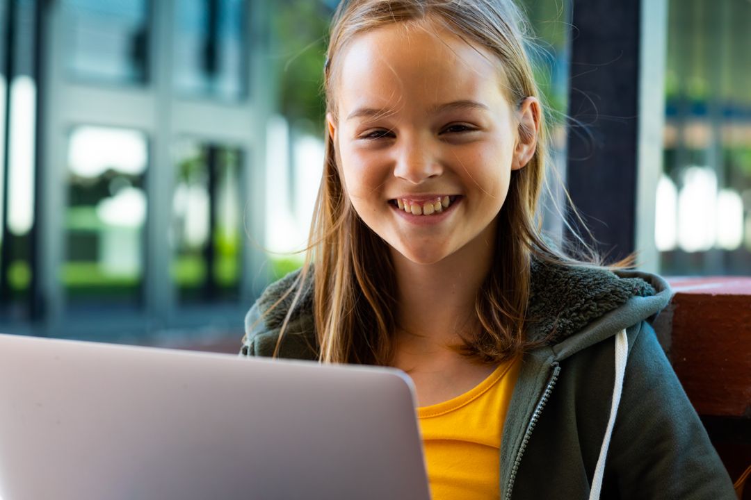 Cheerful Schoolgirl with Laptop Smiling Outdoors
