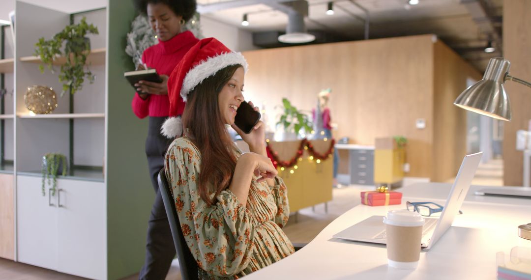 Happy Woman Wearing Santa Hat Working in Office During Christmas - Free Images, Stock Photos and Pictures on Pikwizard.com