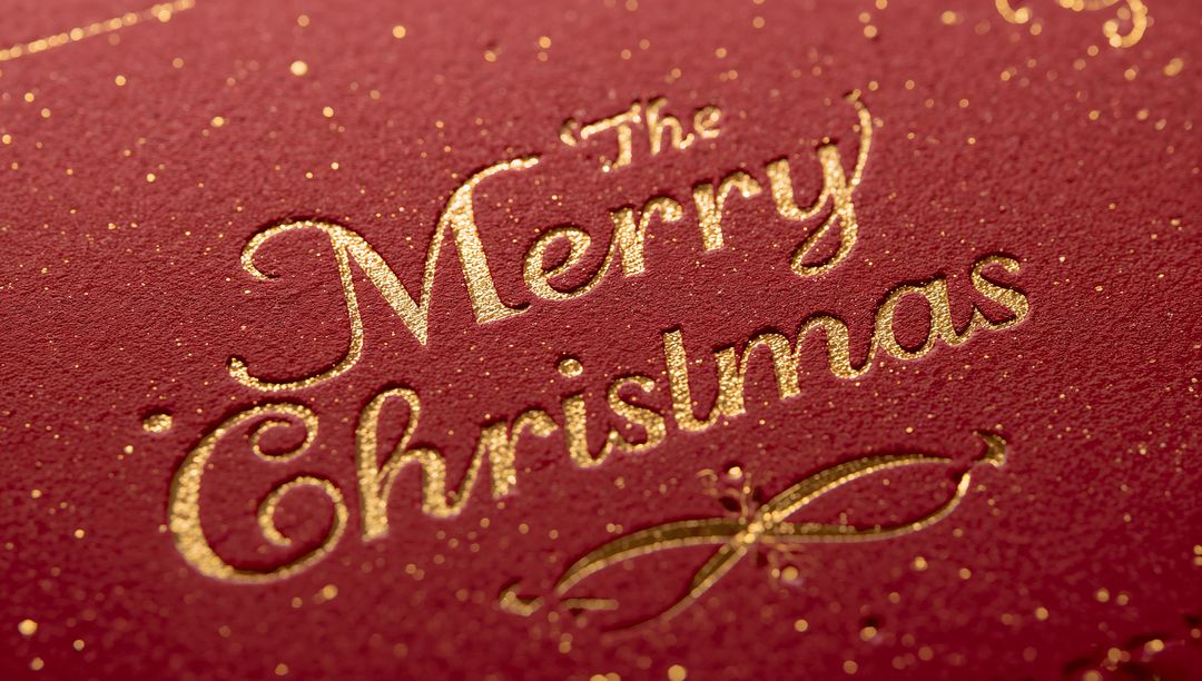 Merry Christmas Gold-Foil Embossed Card Shimmering on Red Textured Paper Closeup