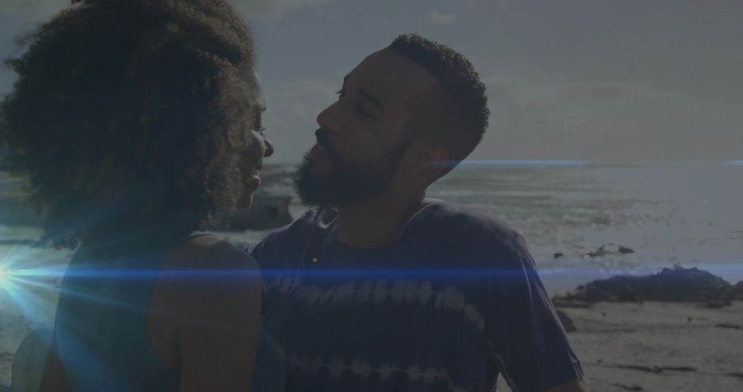Couple Embracing on Backlit Rocky Beach with Sun Flare and Ocean Horizon, Silhouette