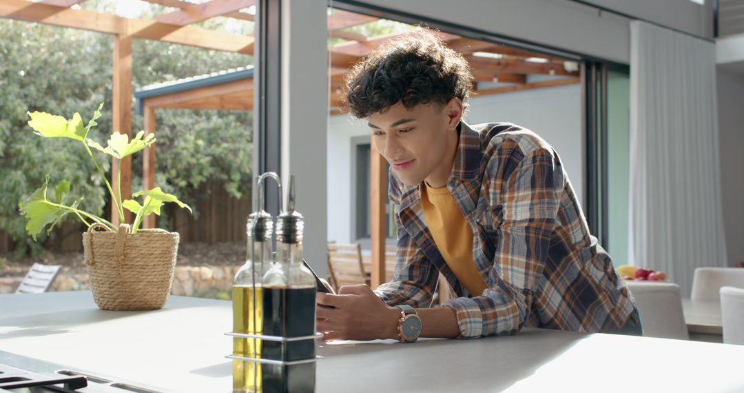 Young Man Leaning on Kitchen Island Using Smartphone