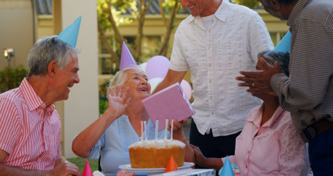 Joyful Seniors Celebrating Outdoor Birthday Party with Cake and Gifts - Free Images, Stock Photos and Pictures on Pikwizard.com