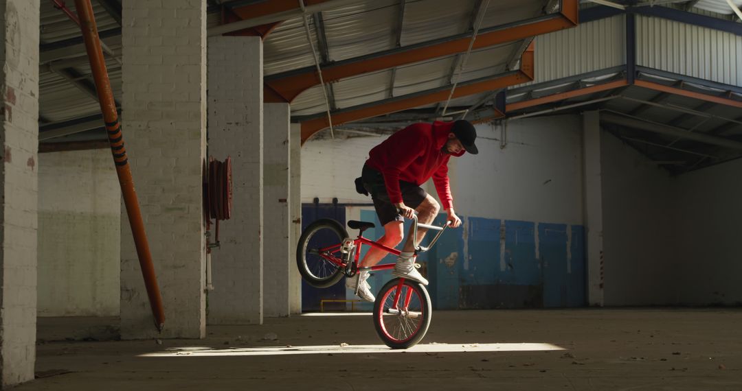 BMX Biker in Abandoned Warehouse Performing Stunt in Red Hoodie - Free Images, Stock Photos and Pictures on Pikwizard.com