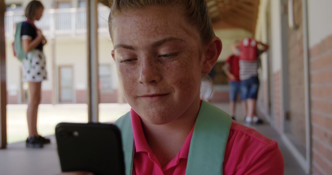 Smiling Schoolboy Connecting on Smartphone in School Hallway