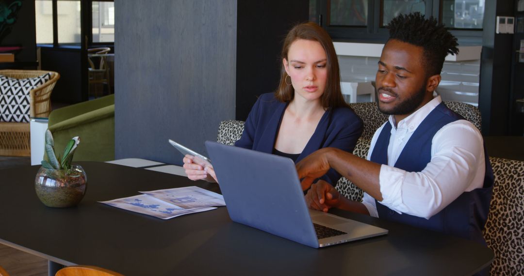 Diverse Colleagues Analyzing Project on Laptop in Modern Office